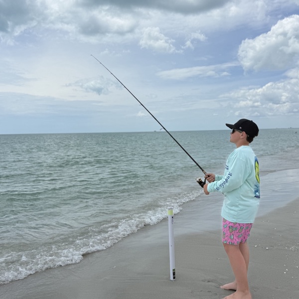 Jack casting his fishing rod from a sandy shoreline